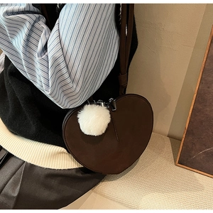 Detailaufnahme der herzförmigen Umhängetasche aus Wildleder mit weißem Pelz-Pompon
