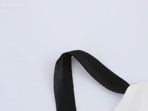 Vue détaillée de la bretelle noire et du tissu plissé blanc d'une robe longue
