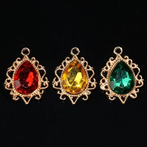 Pendentifs vintage en forme de goutte avec cadre dentelle et strass colorés sur fond noir