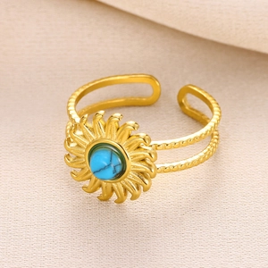 Detail of gold sunflower ring with turquoise center on beige fabric background