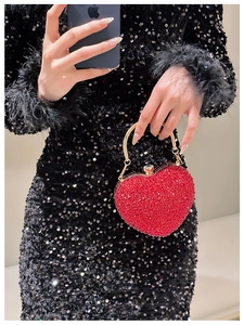 Macro view of heart-shaped luxury evening bag with red crystals and gold handle