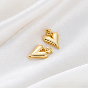 Detail shot of 18K gold-plated heart pendant on white silk showing high polish finish