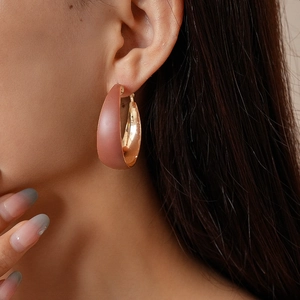 Close-up of a matte pink and rose gold geometric hoop earring on a female model