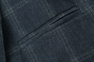 Gros plan sur la texture à carreaux fins et la poche passepoilée d'un blazer décontracté