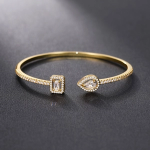 Macro shot of gold cuff bracelet featuring square and pear shaped zircon stones