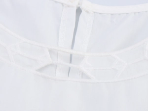 Détail d'un haut blanc sans manches avec broderie et découpe ajourée sur l'encolure