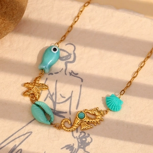 Detail of 18K gold-plated ocean necklace with starfish and seahorse charms on beige paper