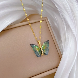 Detailed close-up of a golden butterfly pendant with blue-green gradient wings on white silk