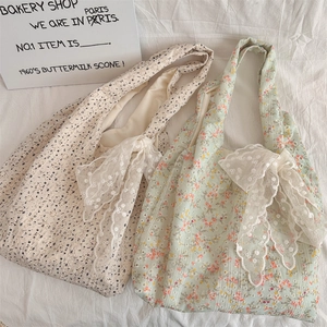 Detail view of floral canvas tote bags with large lace bows in creamy white and light green