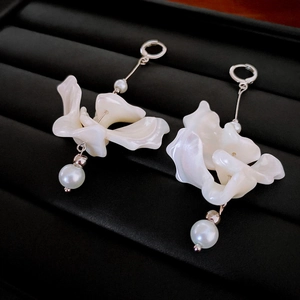 Gros plan sur boucles d'oreilles perles irrégulières et franges sur fond cuir noir