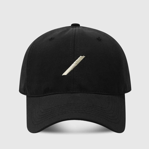Close-up of black cotton baseball cap showing detailed white slash embroidery and fabric texture