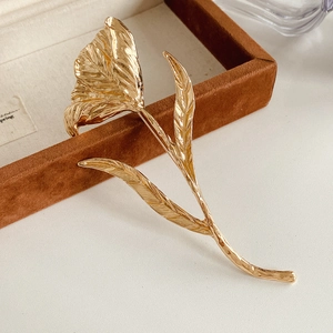 Close-up of golden flower brooch with hammer texture and metallic glossy finish
