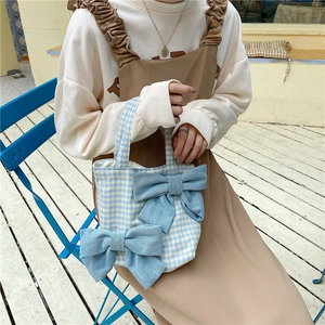 Detail of blue and yellow plaid handbag with large denim bows and fabric texture