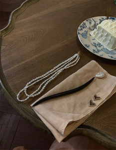 Three-layer baroque pearl necklace with heart earrings on a wooden tabletop setting