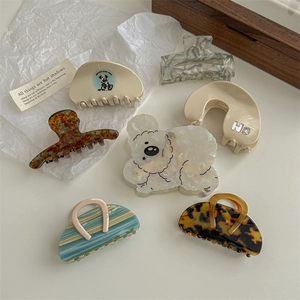 Set of minimalist acetate hair claws including puppy and tulip designs on a tray