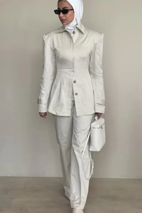 Detail of elegant beige blazer suit with waist-cinched top and straight trousers