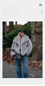 Detail of grey faux fur coat featuring a wide collar and fluffy texture in outdoor setting