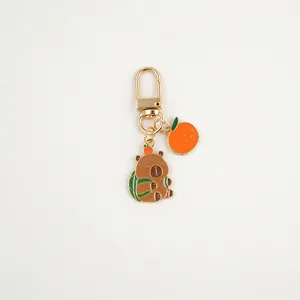 Cute brown capybara keychain with green turtle shell and orange detail on white background