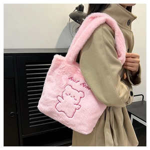 Détail de la texture d'un sac en peluche rose avec un ours brodé et texte Bear Bear