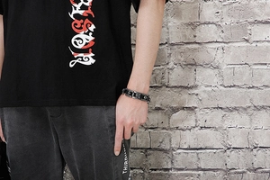 Bracciale punk largo con teschi e croci in rilievo indossato sul polso maschile