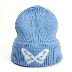 Close-up of light blue ribbed knit beanie featuring a white butterfly jacquard pattern