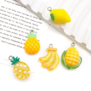 Detailed view of yellow resin fruit charms including pineapple, lemon and corn for DIY jewelry