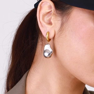 Gros plan de boucles d'oreilles bicolores avec anneau doré et pendentif argenté irrégulier