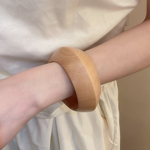 Détail d'un large bracelet en bois massif montrant le grain naturel sur un poignet