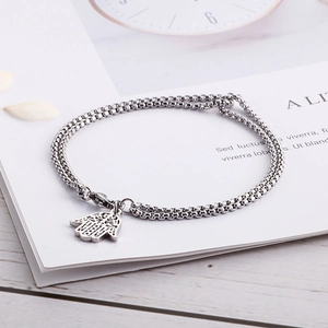 Dettaglio del bracciale argento a doppia catena con ciondolo mano di Fatima su petali