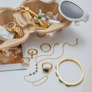 Close-up of gold-plated stainless steel jewelry collection with green zircon gemstones