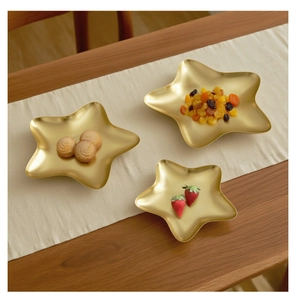 Detailed view of three-piece star-shaped gold metal serving trays on a wooden table