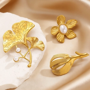 Detail of gold ginkgo leaf and flower pins with pearls on silk and stone background