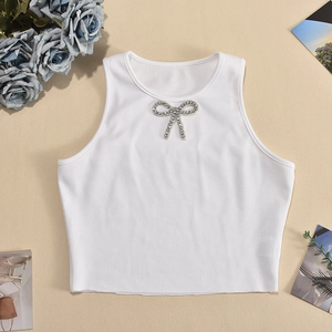 Detail of white ribbed knit crop top featuring rhinestone bow accent on neckline