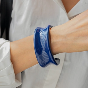 Détail du bracelet rigide en résine bleu foncé avec finition brillante sur manche blanche
