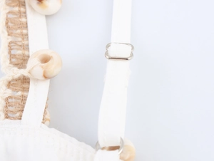 Detailed shot of white bohemian dress with adjustable strap and decorative shell detail