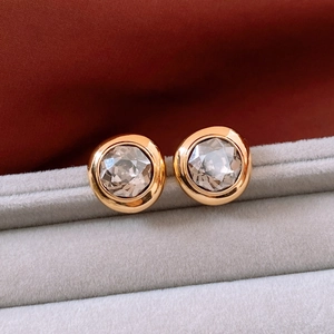 Macro shot of 18K gold-plated oval stud earrings with champagne crystal in a red gift box