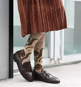 Close-up of vintage beige socks with floral and insect prints paired with loafers
