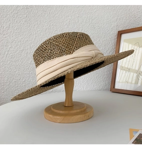Close-up of handmade seagrass sun hat featuring a wide cream pleated fabric ribbon