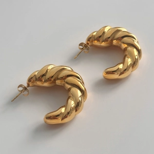 Macro shot of 18k gold plated hollow twisted hoop earrings with polished metal texture