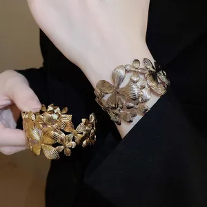 Manchette dorée évidée à motifs floraux avec texture brossée radiale sur veste noire