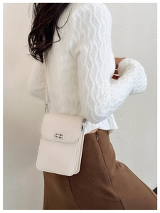 Close-up of cream mini vertical crossbody bag with silver twist lock and slim strap