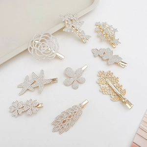 Detailed view of nine gold alloy hair clips with rhinestones in flower and leaf shapes