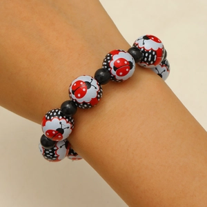 Gros plan du bracelet élastique perlé avec des motifs de coccinelles rouges blancs et noirs