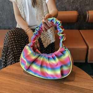 Detail showing rainbow gradient pleated shoulder bag held by a model in a casual setting