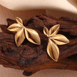 Macro shot of 18K gold plated leaf earrings on rustic wood texture with soft lighting