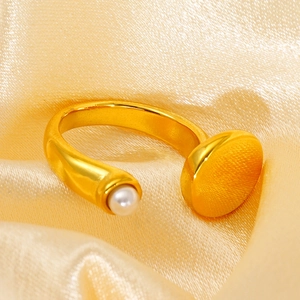 Detail of gold-plated geometric ring featuring a white pearl on golden silk fabric