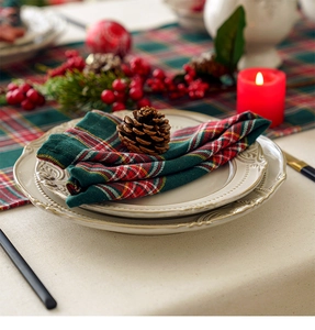 Close-up of a red and green plaid cotton linen napkin with a pinecone on ceramic plates
