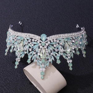 Detail of silver bridal crown featuring mint green and clear crystals on a dark backdrop