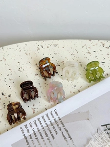 Detailed view of six colorful acetate mini hair claws arranged on a vintage paper background