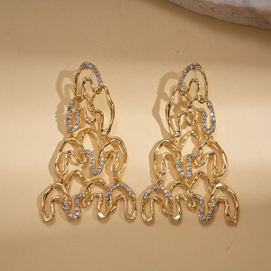 Detailed close-up of gold geometric twisted wavy earrings with sparkling rhinestones